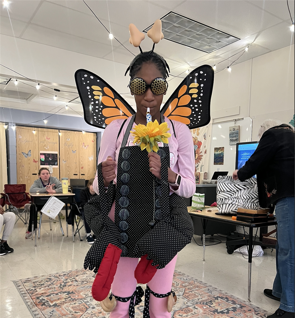  A students looks at a camera for a photo dressed up in a butterfly costume.